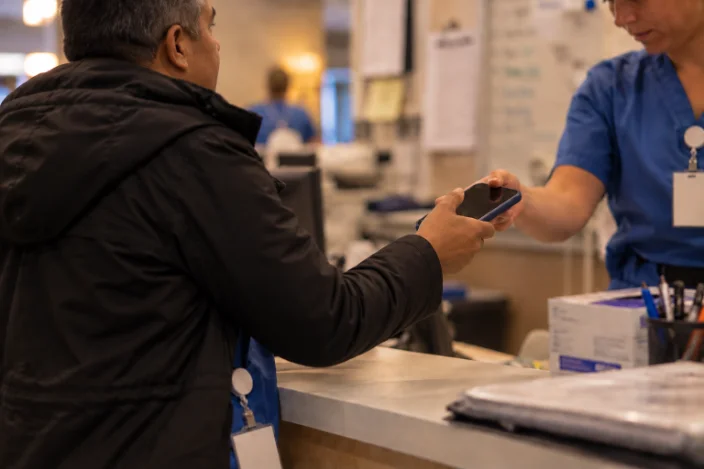 Back at the nurses' station, a coworker hands the nurse his phone.